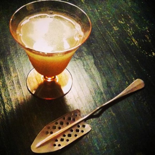 An absinthe spoon on a green countertop