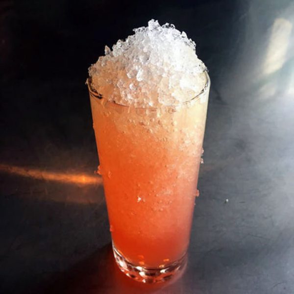 Crushed ice with bright red drink in highball glass