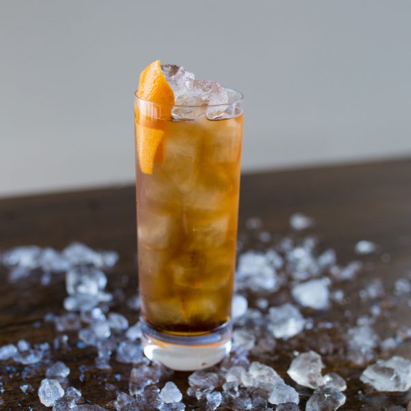Crushed ice on a wooden table with a highball cocktail