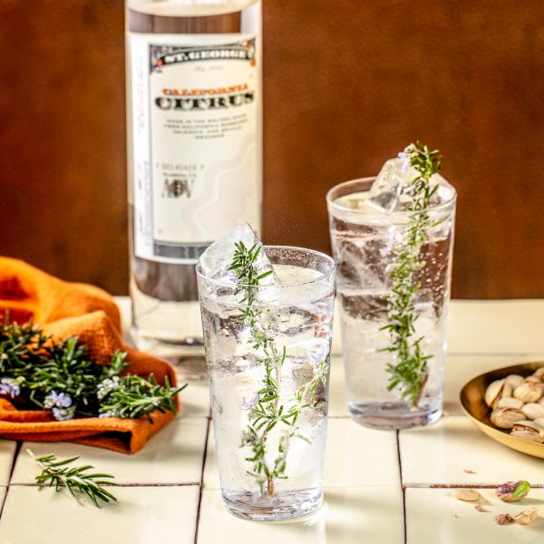 rosemary garnished clear bubbly drinks with a bottle of vodka