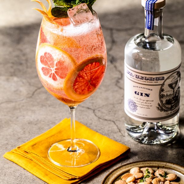 A wine goblet packed with citrus slices and a bottle of gin
