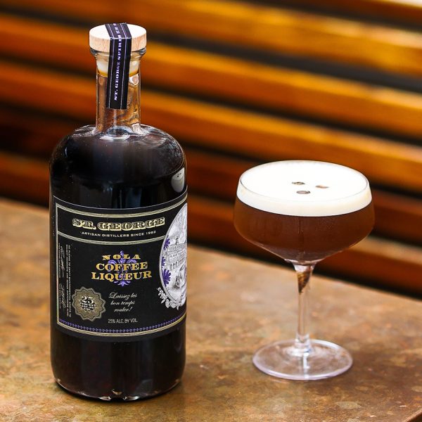 A bottle of St. George NOLA Coffee Liqueur with an espresso martini in a coupe glass next to it.