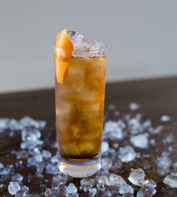 Crushed ice on a wooden table with a highball cocktail